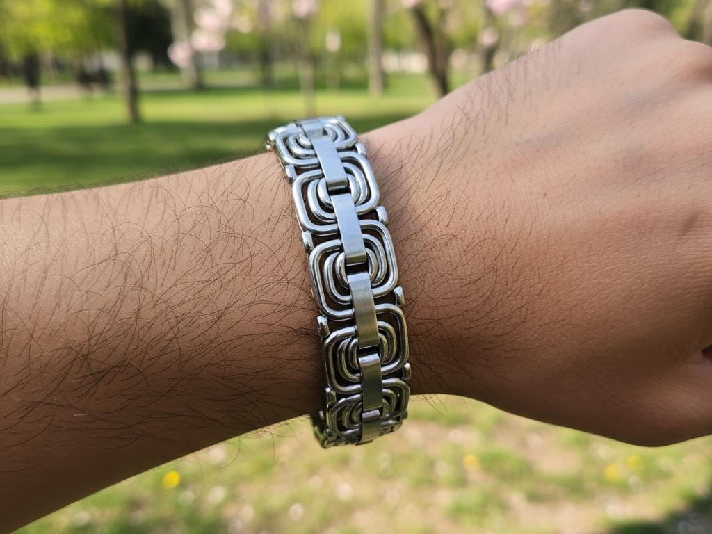 Close-up of a Turkish man's wrist wearing a stylish stainless steel Italian bracelet outdoors in a green park with sunlight highlighting the bracelet's intricate chain design.